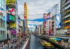 Dotonbori canal in central Osaka lined with restaurants, shops, and tourists on a busy afternoon